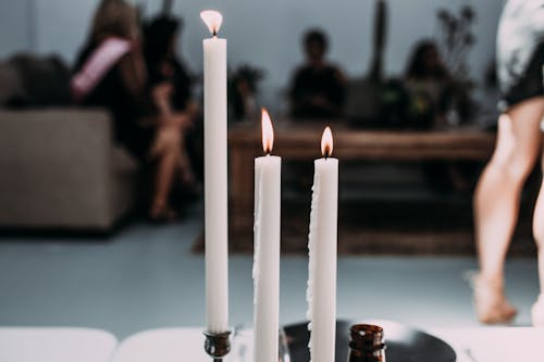 Burning candles from wax in candlestick on table in modern cafe during festive