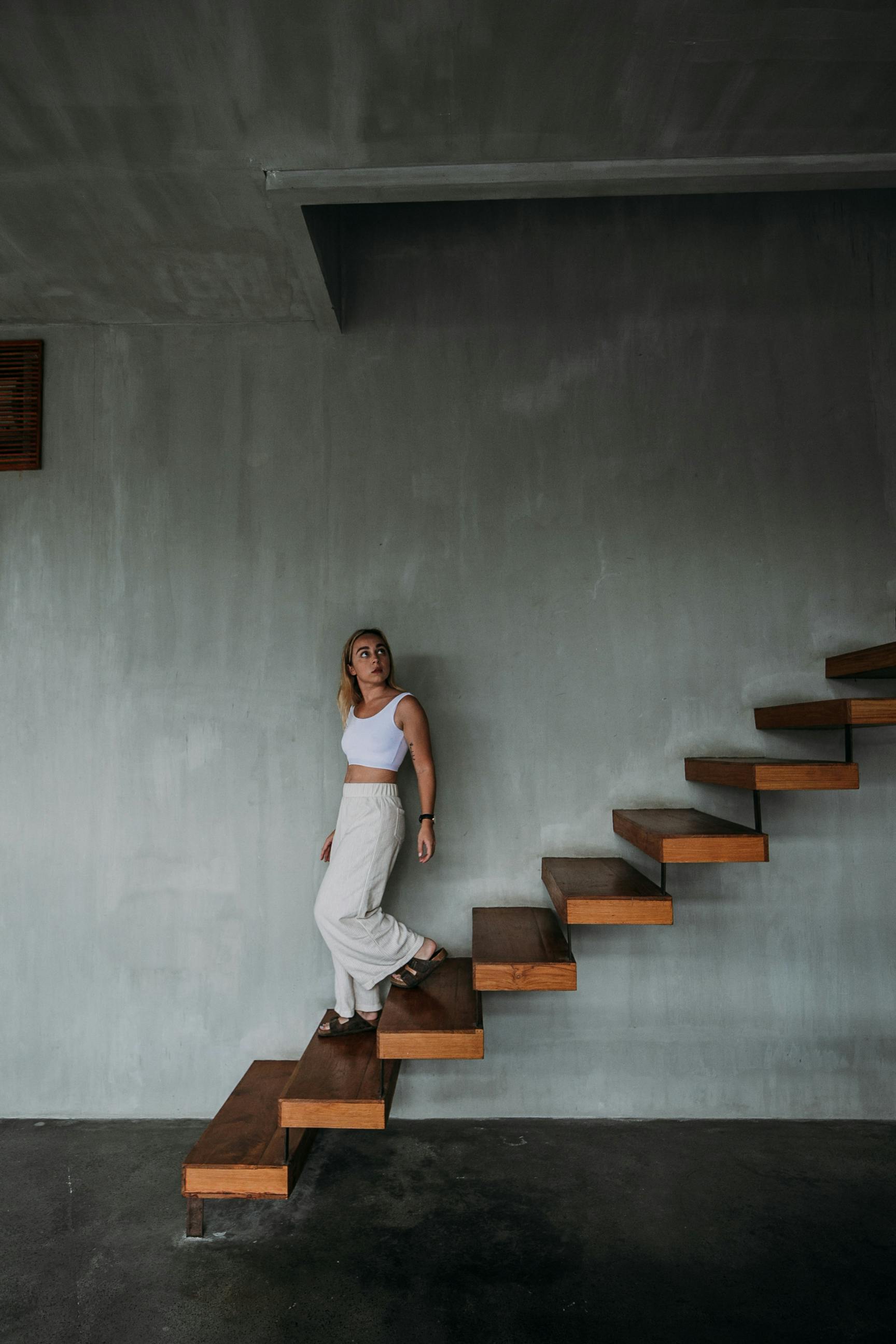 Indoor portrait of a young beautiful fashionable business woman posing in  loft interior. Model looking through window. Lady wearing stylish clothes. Female  fashion concept. Dark background. Waist up Photos