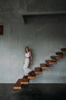 一位穿着休闲装的苗条女性正低头思考着走下楼梯