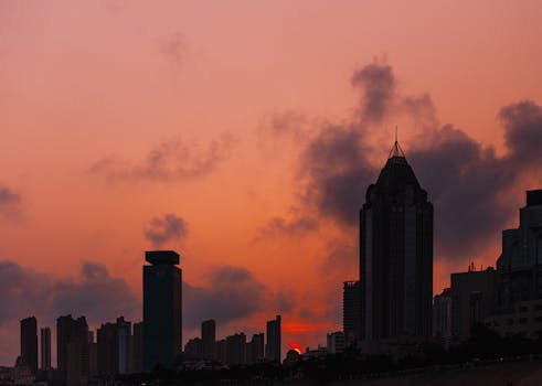 A striking cityscape with silhouetted skyscrapers against a vibrant sunset sky.