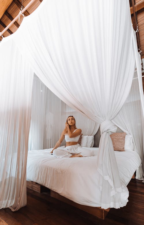 Free Woman relaxing on canopy bed at home Stock Photo