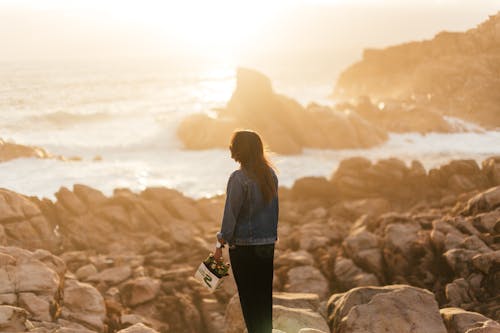 Faceless woman on sandy coast of ocean