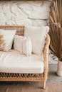 Wicker sofa with decorative cushions near stone wall