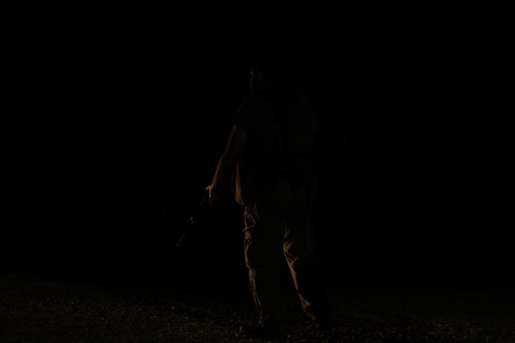 Unrecognizable Person In Darkness On Black Background