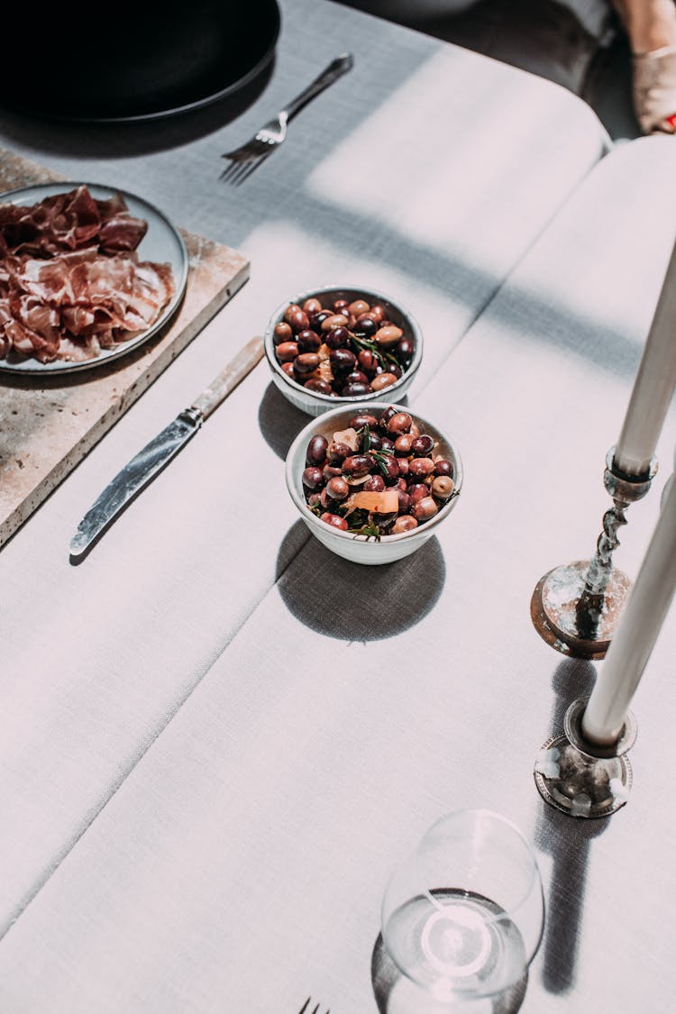 Assorted Beans In Bowls Near Smoked Ham On Table