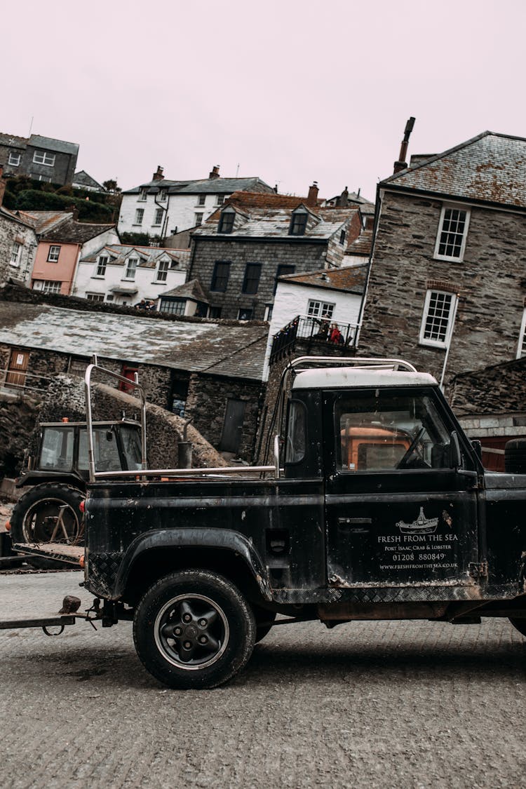 Old Car Riding On Pavement Near Aged Houses