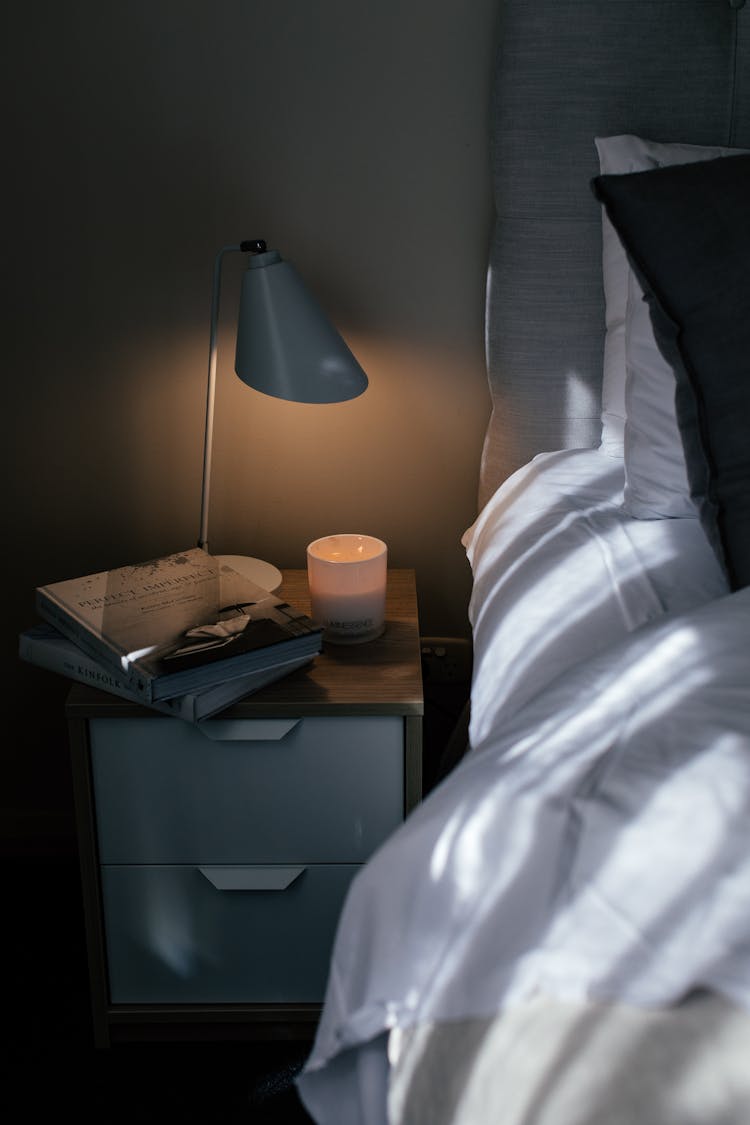 Books And Lamp On Bedside Table In Hotel Room