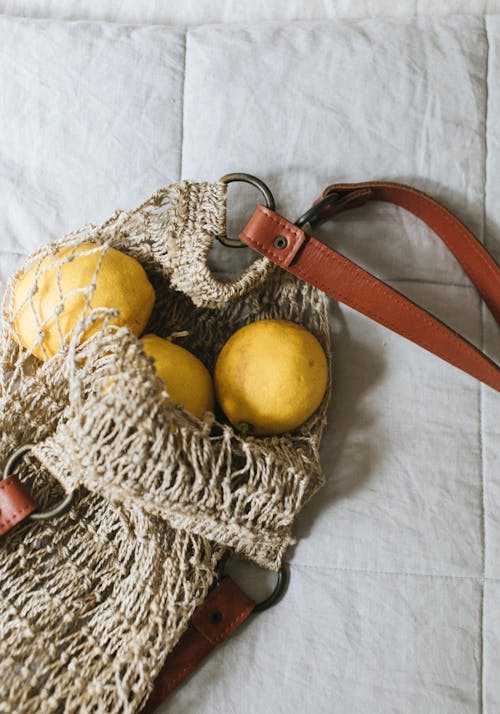 Free From above of delicious fresh quinces in ecological bag with leather strap on crumpled duvet Stock Photo