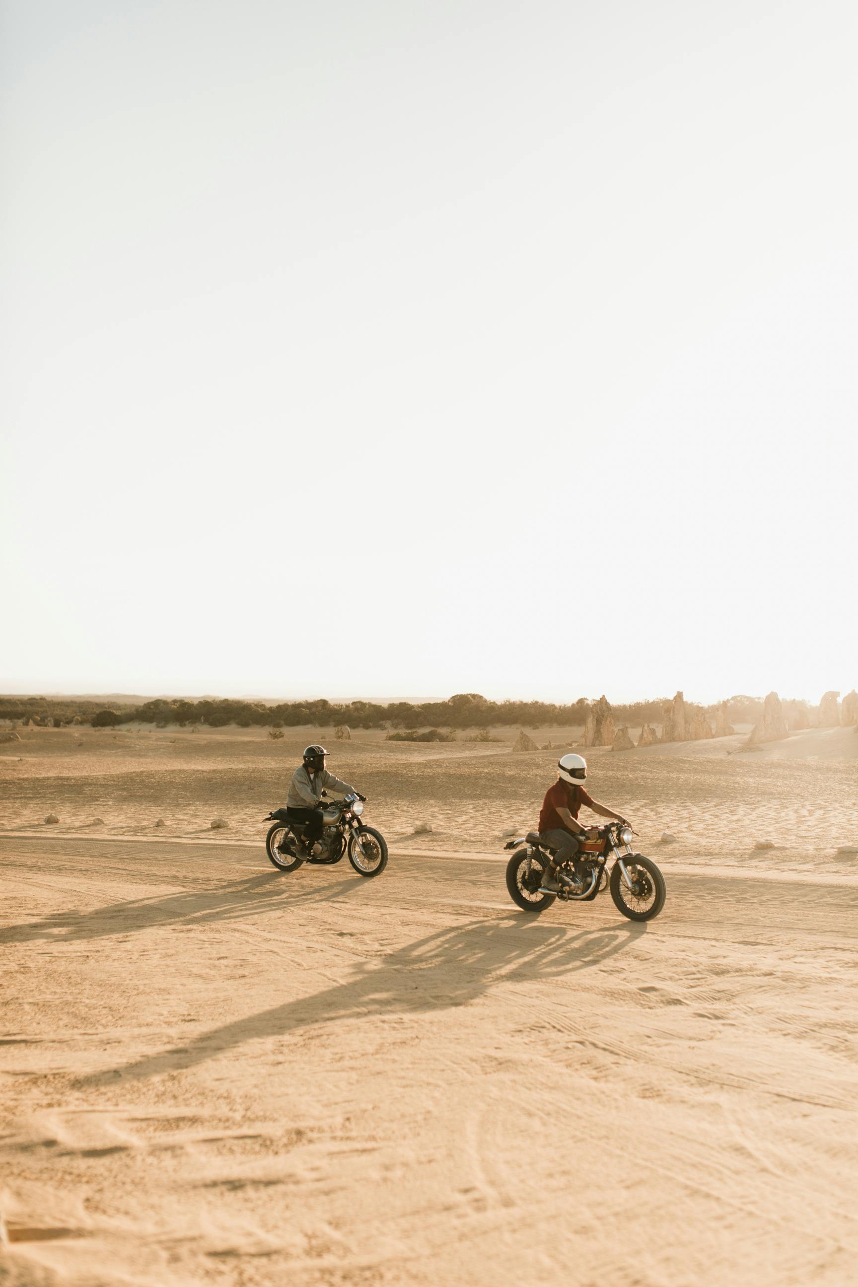 unrecognizable bikers riding motorcycles in desert in sunlight