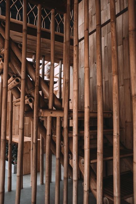 Oriental house interior with bamboo sticks forming fence near empty staircase and wall in daylight