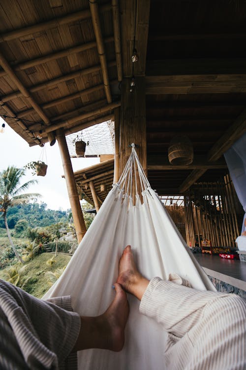 Faceless tourist resting in hammock in tropical resort