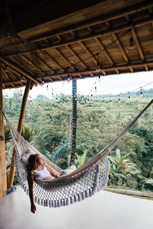 Free Relaxed female tourist contemplating nature from hammock on terrace Stock Photo
