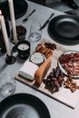 From above of different types of cheese and smoked meat slices on plate near bunch of fresh grapes