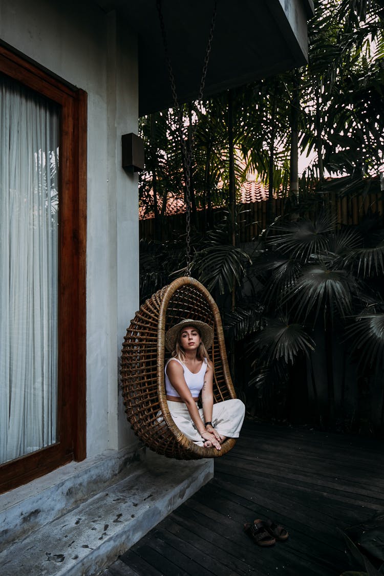 Feminine Woman Resting In Hanging Chair Near House