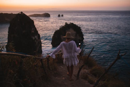 Woman walking towards blue sea at sunset