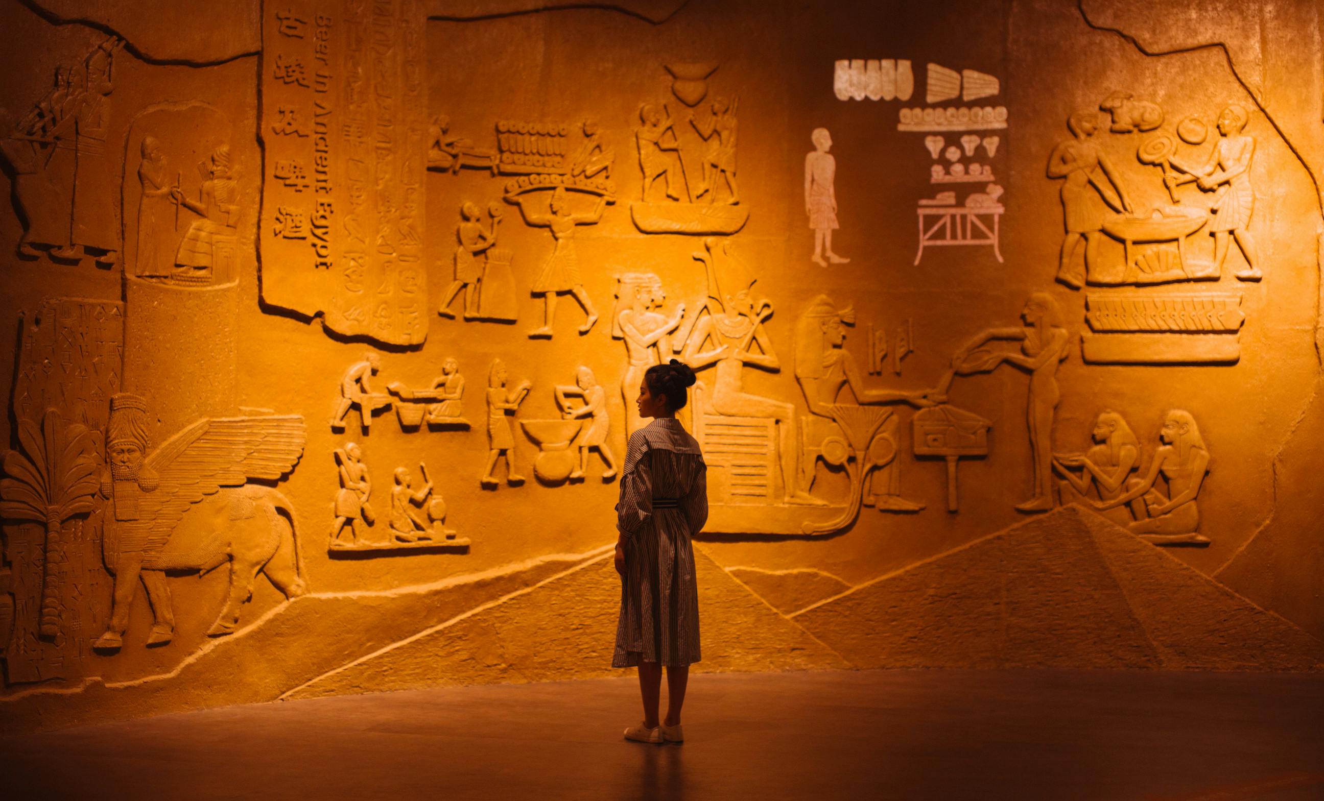 woman standing near old stone wall with carved images
