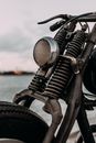 Old fashioned chopper with headlight and brake lever near rippling river in evening