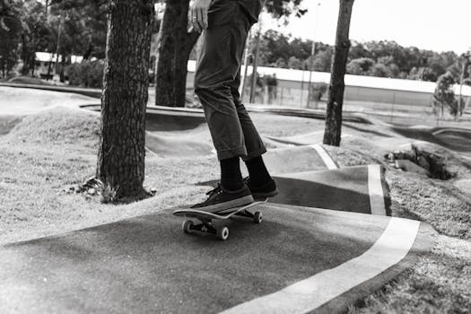 A skateboarder enjoying a black and white ride on a winding track in an urban park.