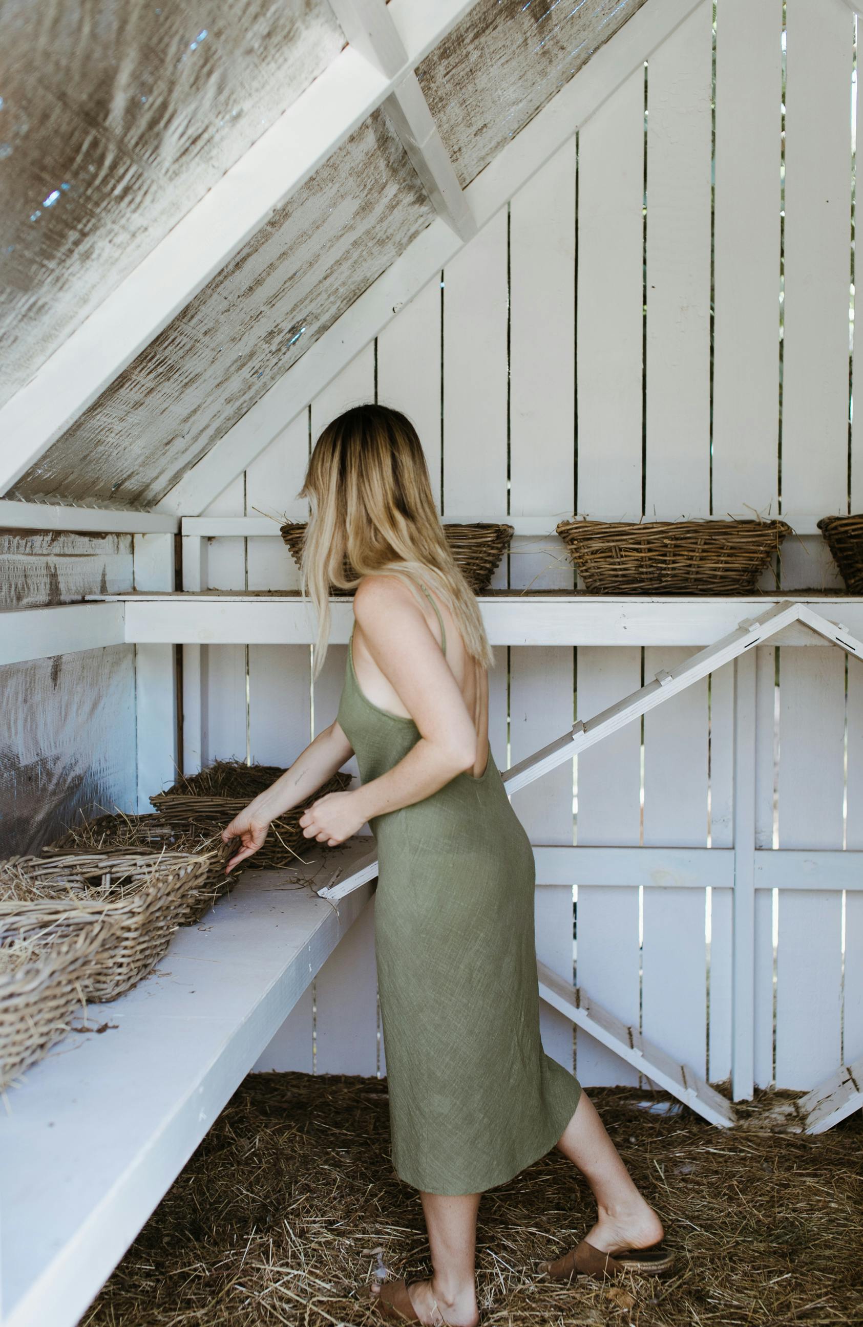 woman standing in barn with straw baskets