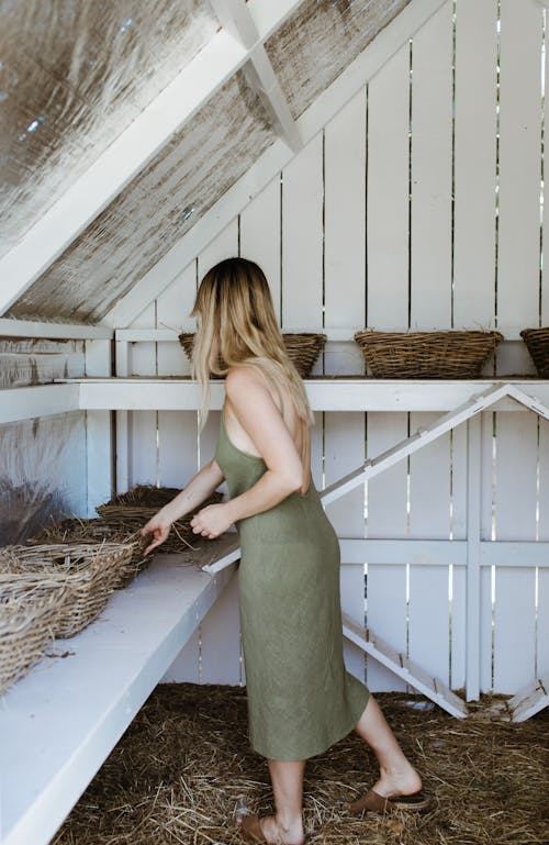 Woman standing in barn with straw baskets