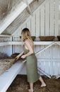 Woman standing in barn with straw baskets