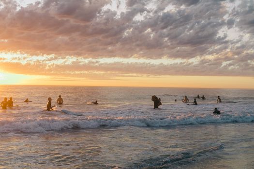 夏夜，游客们穿着泳衣，在海浪中游泳、戏水，欣赏着海景