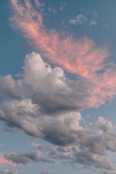 A stunning vertical shot of dramatic clouds with pink hues in the sky, perfect for nature themes.