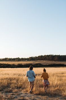 一对夫妇在风景如画的开阔田野上散步，夏日天空晴朗，他们享受着平静，捕捉到一种自由与宁静的感觉
