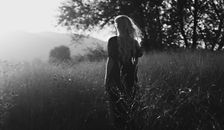 Anonymous traveler contemplating mountain in field in summer