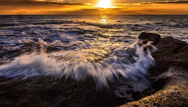 Wavy Ocean Under Sky With Bright Sun At Night