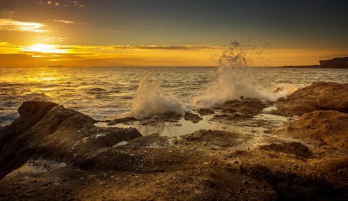 Splashing sea water under bright sky at sundown