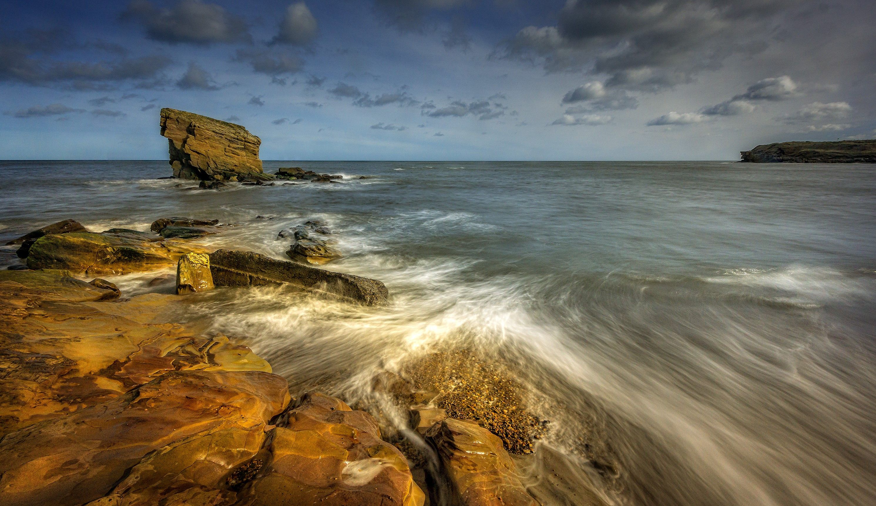 Fast ocean water stream near rocky formations under sky · Free Stock Photo