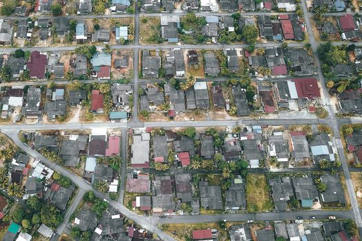 Drone view of roofs of aged residential houses near straight roads in suburb