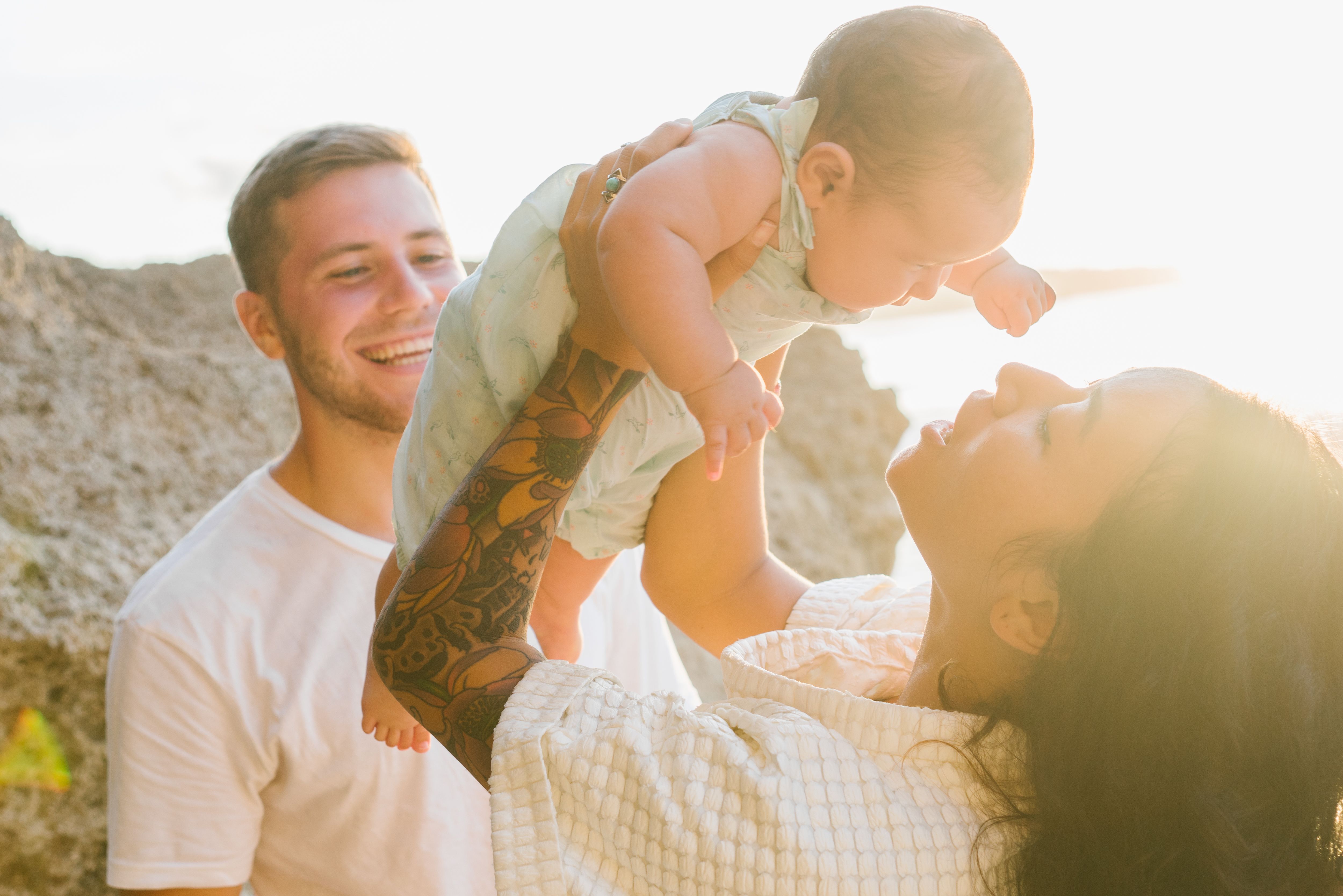 A cheerful family enjoying a sunny day at the seaside with a baby.