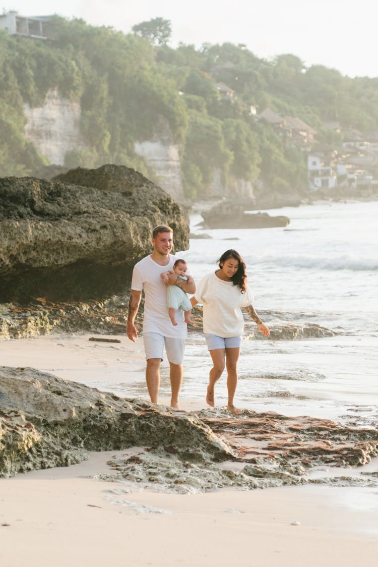 Couple Walking With Baby On Beach