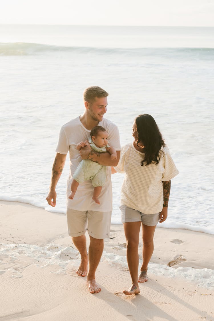 Couple Walking On Beach With Baby