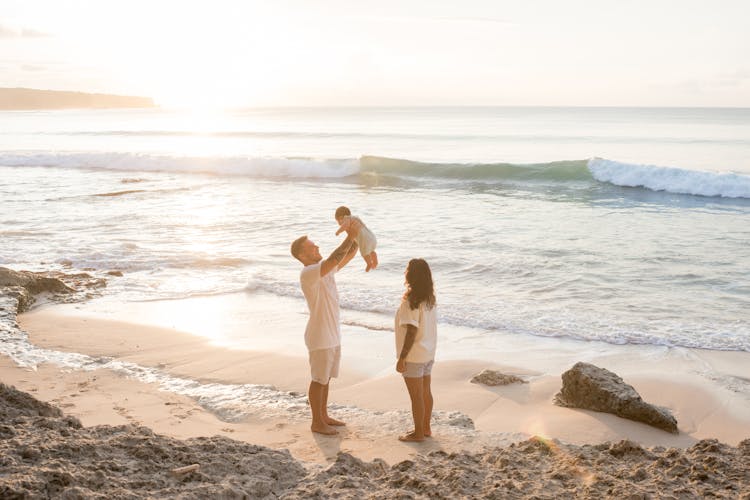 Father Raising Baby Up On Beach