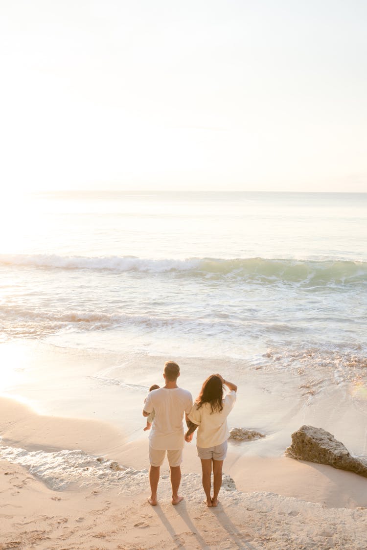 Couple Standing On Beach With Baby