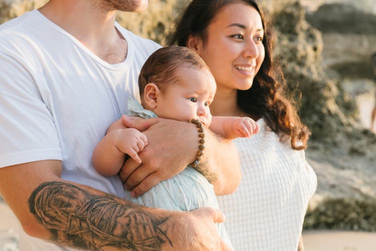 A Man Carrying A Baby Beside A Woman