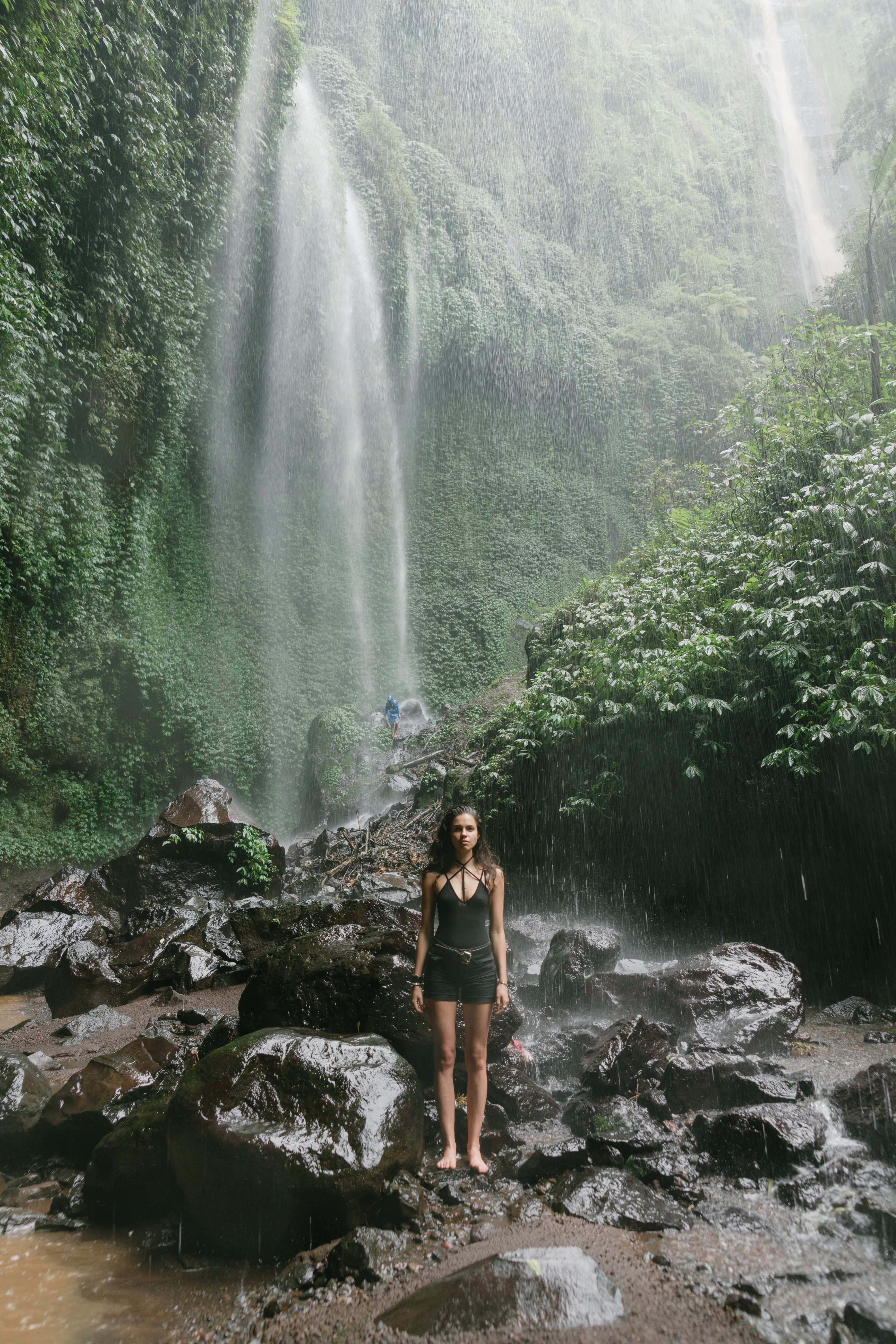 A Woman Standing on a Rock Near Waterfalls · Free Stock Photo