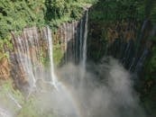从空中俯瞰，瀑布令人惊叹，四周环绕着郁郁葱葱的绿色植物，雾气弥漫，彩虹浮现