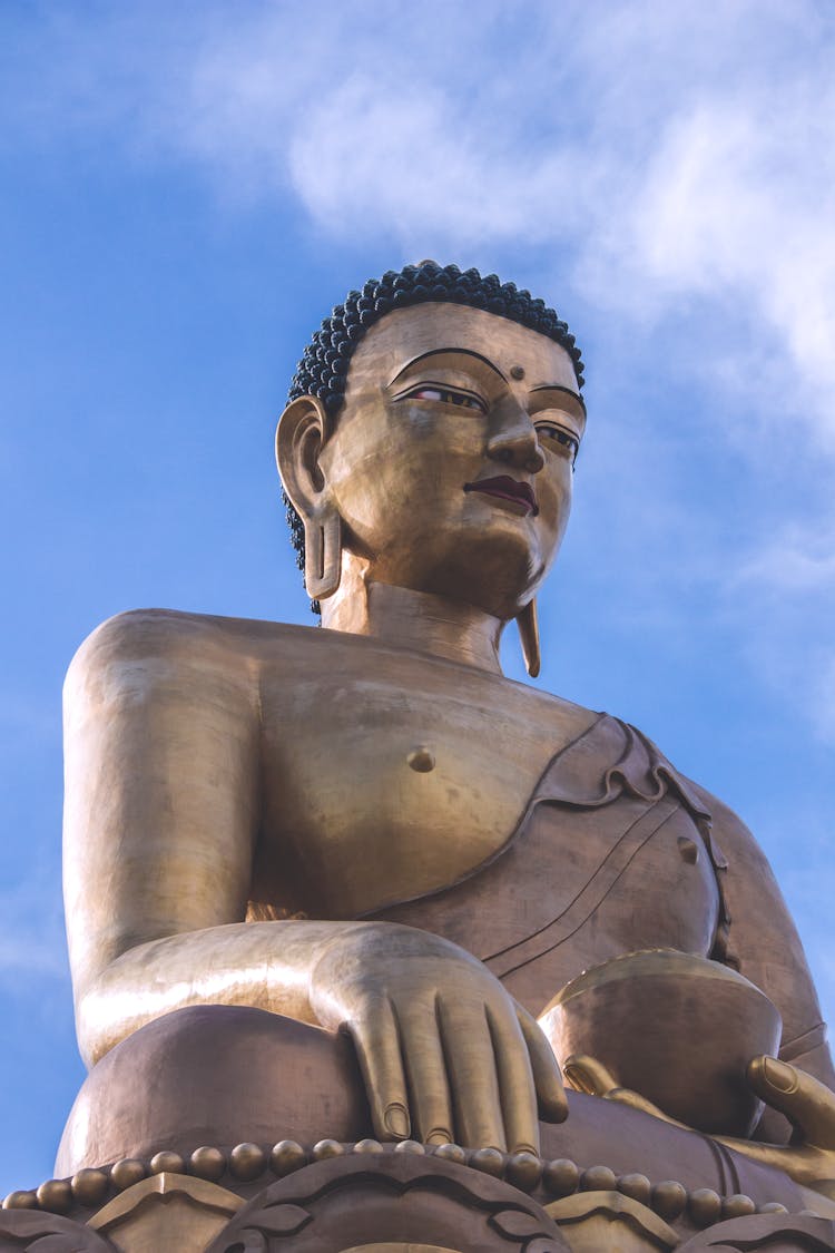 Bronze Statue Of Buddha Against Blue Sky