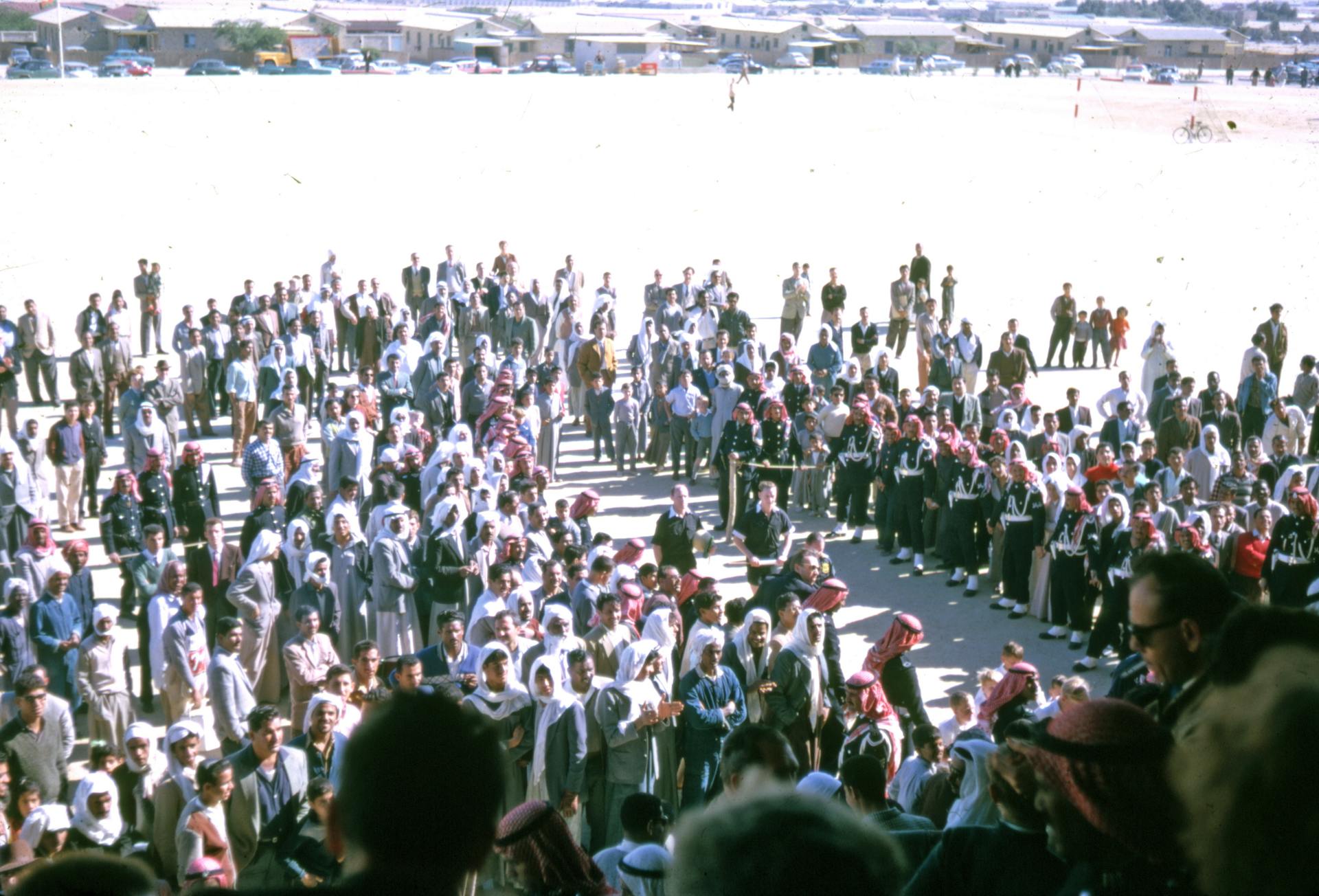 A large crowd gathers outdoors under sunny conditions in Saudi Arabia.