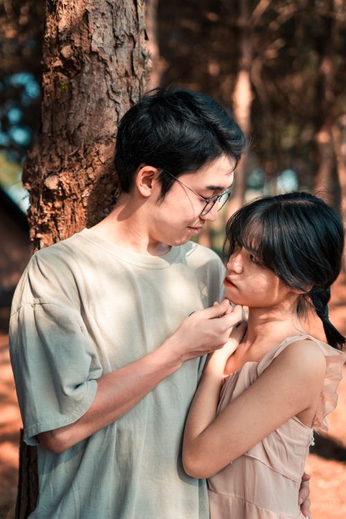 Free Loving Asian couple standing close to each other in forest in sunny day and looking at each other Stock Photo