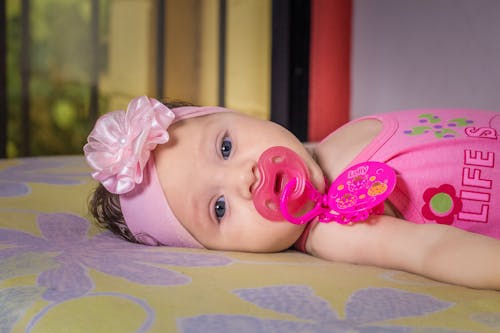 Free Cute infant in pink headband lying on bed Stock Photo