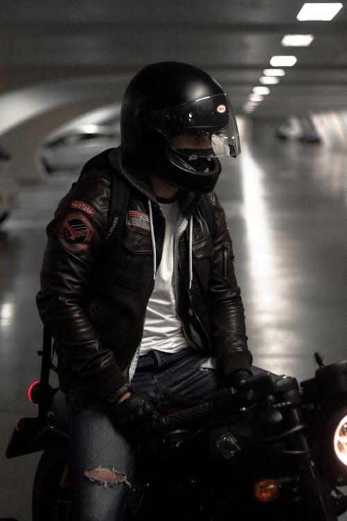 Anonymous man sitting on motorbike in modern parking