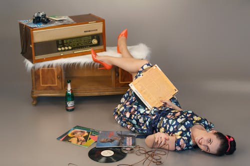 Happy woman lying on floor near vintage disks and record player