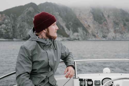 Free Man with beard and knit cap on boat with foggy cliffs in background. Stock Photo