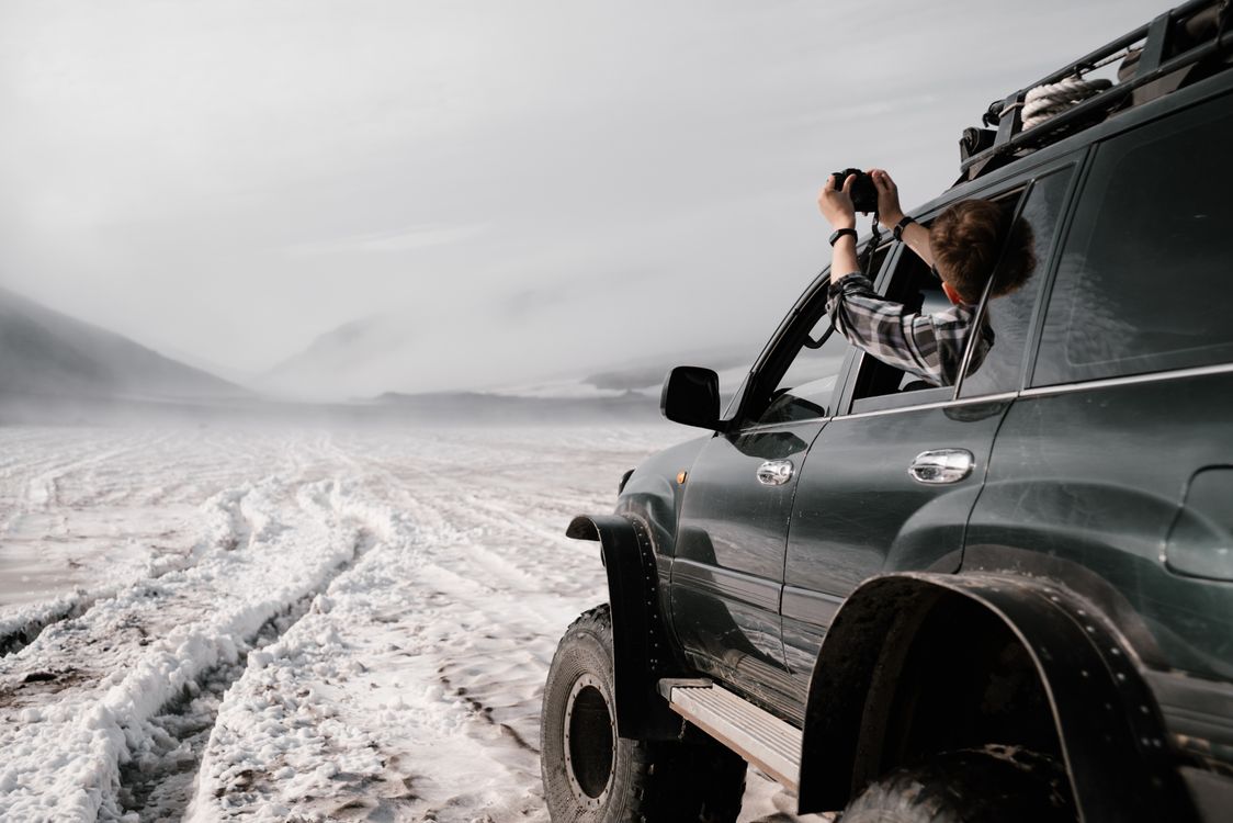 Free Adventurer in SUV captures snowy terrain and foggy mountains during daytime exploration. Stock Photo