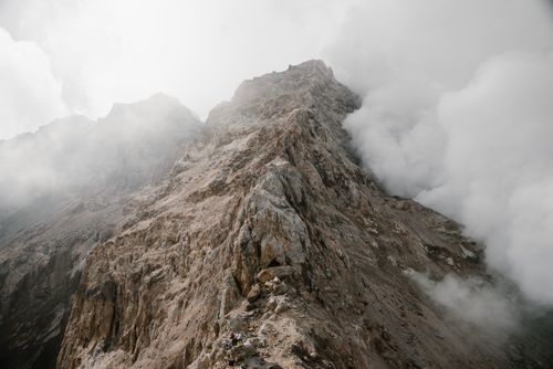 Free A stunning view of rugged mountain peaks enveloped in clouds, capturing nature's raw beauty. Stock Photo